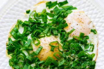 Fried eggs with green onions on a white plate.Breakfast with eggs.