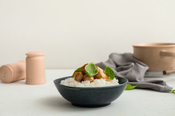 Bowl with boiled rice and chicken on table