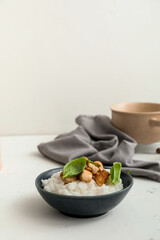 Bowl with boiled rice and chicken on table