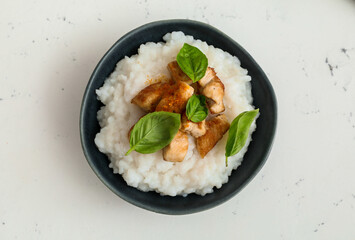 Bowl with boiled rice and chicken on white background