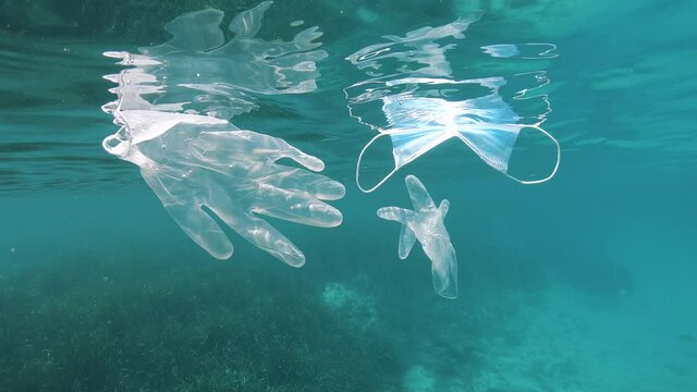 Face mask and gloves float under water surface in the sea, plastic waste pollution since coronavirus COVID-19 pandemic, Mediterranean sea, France