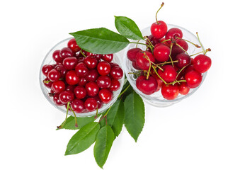Various cherries in two glass cups, cherry leaves, top view