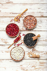 Different raw legumes on white wooden background