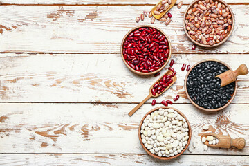 Different raw legumes on white wooden background