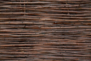 Background in the form of a fence woven of twigs, horizontal rods. Decorative fence