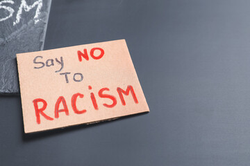 Placard with text SAY NO RACISM on dark background