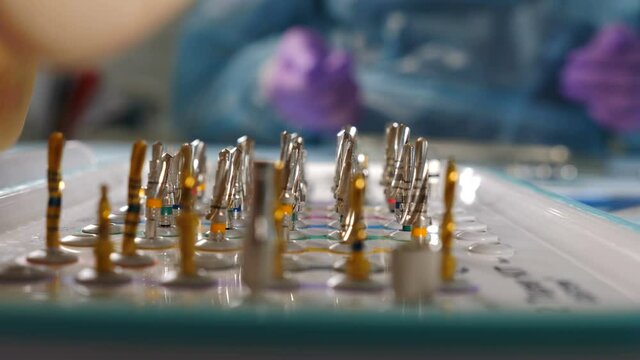 Healthcare concept. dentist choosing and taking bor for teeth drilling in modern dental office, close-up view. sterile appropriate drill for dental instrument. 4 k footage