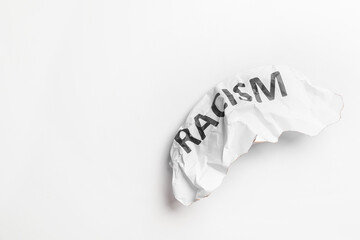 Crumpled paper with text RACISM on white background