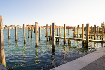 Venice, Italy. Typical landscape view of the lagoon, rawn of mooring poles in perspective with the peculiar venetian architecture in the background.