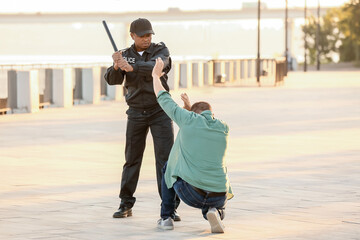 Aggressive African-American police officer mistreating man outdoors