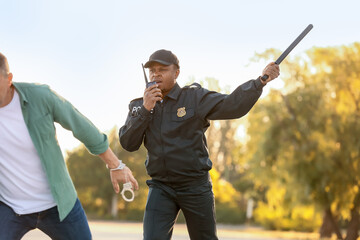 Aggressive African-American police officer mistreating man outdoors
