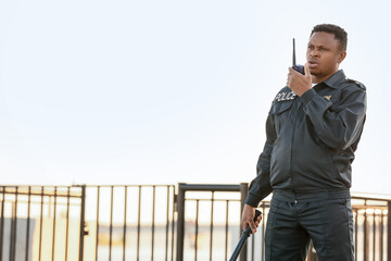 African-American police officer with two-way radio outdoors