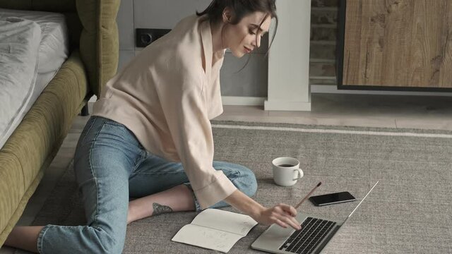 Young positive pleased woman indoors at home using laptop computer
