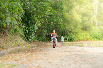 Child boy on a bicycle in the tropical forest. Boy cycling outdoors.