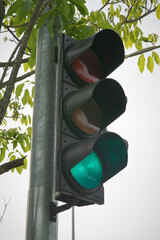 Green traffic light with red walking light for pedestrian in the background. Selective focus.