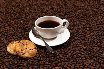 White coffee mug and cookies on the coffee beans background