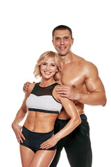 Portrait of happy fit sporty man and woman hugging on white background