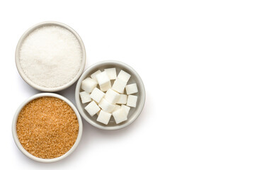 Three various types of sugar(sugar cubes,brown granulated sugar and white sand sugar) in bowl and spoon isolated on white background. Top view.Flat lay. Copy space for text and content.  