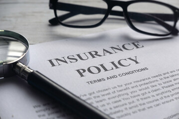 Selective focus of magnifying glass,glasses and Insurance Policy letter on a white wooden...