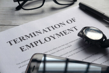 Selective focus of watch,mobile phone,pen,glasses and Termination of Employment letter on a white...