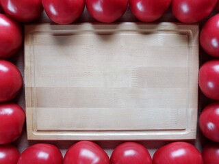 wooden rectangular background around which lies ripe tomato