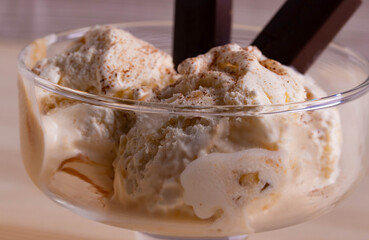 delicious creamy milky vanilla ice cream with caramel and chocolate addings in a glass container 