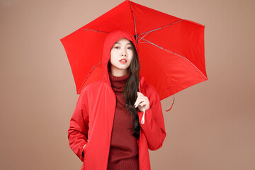 Asian woman with raincoat and umbrella outfit, Isolated mocha brown background