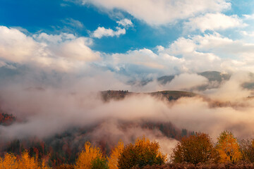 Foggy mountains under sky with clouds.
