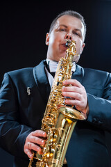 Fototapeta na wymiar Portrait of Expressive Male Saxophonist Player Against Black