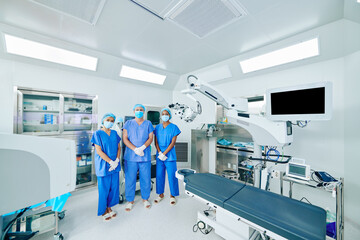Serious medical workers in surgical uniform, masks and gloves standing in operation theater