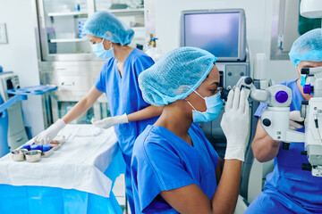 Surgeons performing laser eye vision correction surgery in ophthalmology clinic