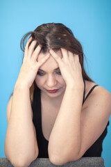 Young attractive caucasian woman holding head with both hands in despair position. Concept of problem, sadness. Female ungroomed, with grease make up, all skin imperfection are visible. Copy space.