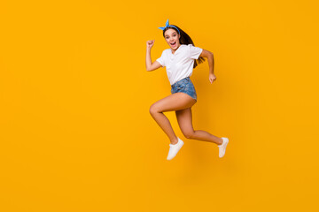 Fototapeta na wymiar Full size profile side photo cheerful enthusiastic girl jump run after spring free time novelty adverts scream wear white t-shirt shoes blue headband isolated shine bright color background
