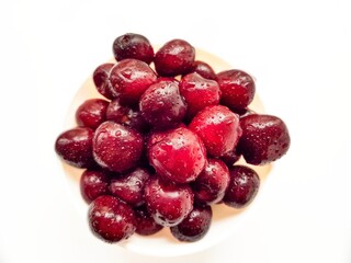 Bright juicy red cherry on a white background in drops of water.
