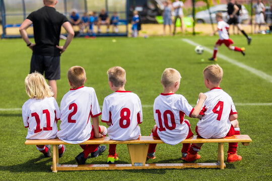 Children Soccer Team Watching Football Match. Children Sport Team in White Shirts. Youth Soccer School Tournament for Children. Young Boys in Soccer Jersey. Football Wooden Bench
