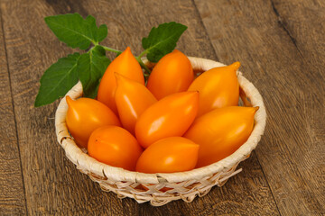 Yellow tomato heap in the wooden bowl
