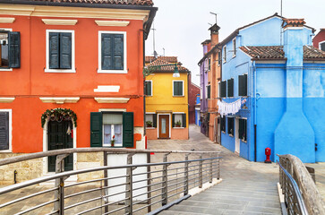 Fototapeta na wymiar Welcome to the famous Burano island! Scenic view with bridge, colored houses and street in the Burano island. Italy.