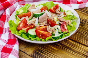 Tasty tuna salad with lettuce and fresh vegetables on wooden table