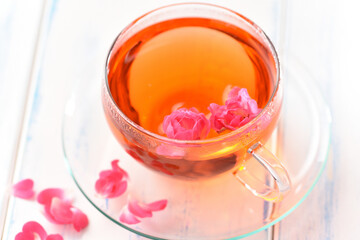 Rose petals tea in a glass cup on the wood table.