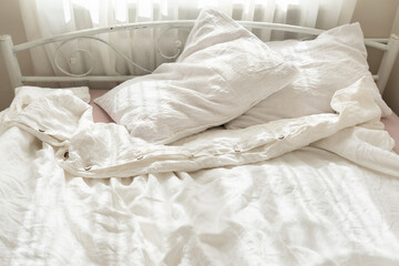 Beautiful morning light in bedroom. Pastel color white bedding. Trendy organic natural linen...