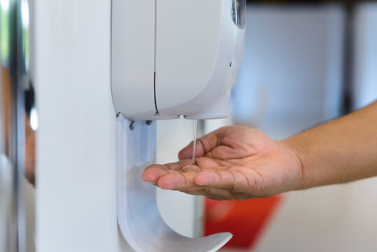 Close-up Hand Male Under Automatic Alcohol Gel Dispenser For Cleaning Hand And Clear Bacteria For Stop Covid 19 Virus Outbreak. Protection Against The Virus, Covid-19, Corona Virus 2019