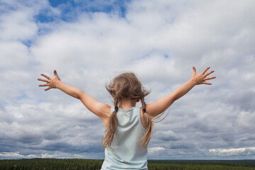 Fototapeta na wymiar Carefree child girl against skyline sky clouds outdoor