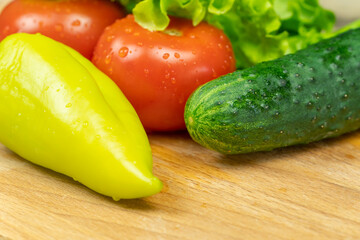 Beautiful, juicy vegetables with water drops Peppers, tomatoes, lettuce leaves, cucumber on a wooden Board close-up