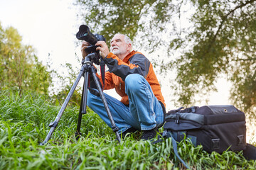 Senior as a nature photographer with camera and tripod