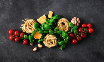Fettuccine with ingredients for cooking italian pasta on dark background top view
