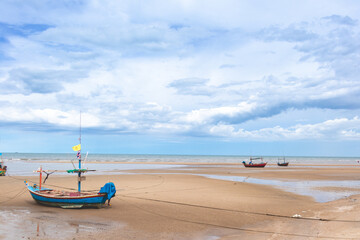 Fototapeta na wymiar Seascape in Thailand with fishing boats on low tide beach and blue sky.