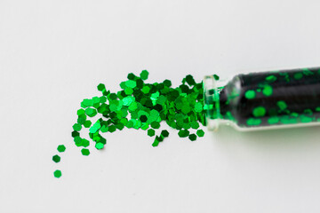 party, decoration and holidays concept - close up of green hexagonal glitters poured from small...