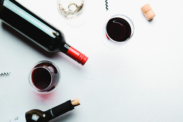 Glasses of red and white wine and bottles on a white concrete background. Flat lay and top view, copy space for text or design