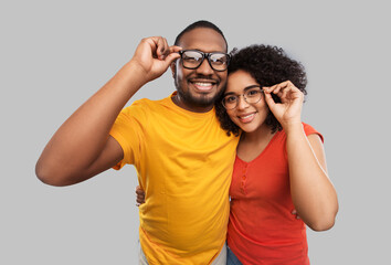 relationships, vision and people concept - happy african american couple in glasses hugging over...