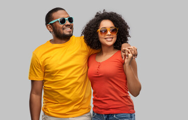 summer, relationships and people concept - happy african american couple in sunglasses over grey background
